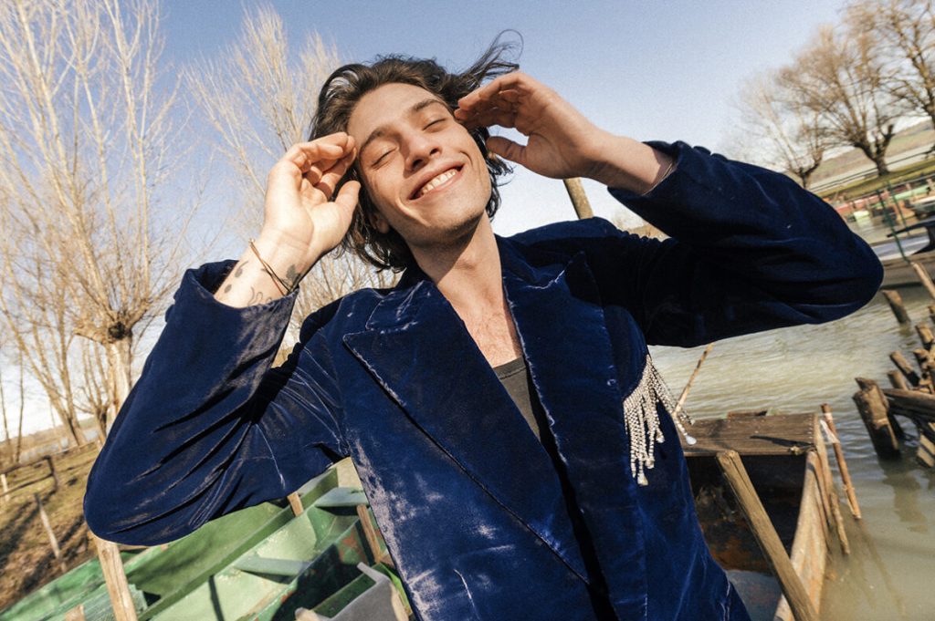un ragazzo che so tocca i capelli e ha indosso un blazer