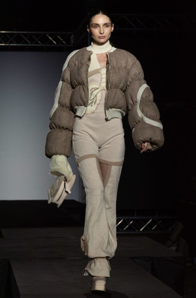 modella che sfila con indosso un look formato da pantalone e bomber