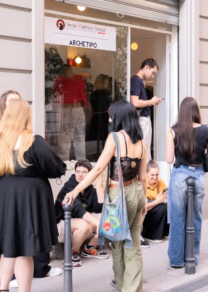 studenti fotografati insieme, alcuni di schiena altri di fronte mentre aspettano seduti fuori da un negozio