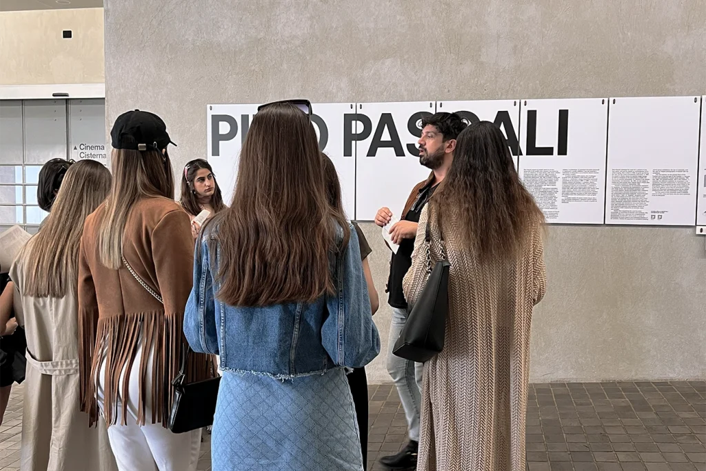 Studentesse in piedi nel museo ascoltano il professore che spiega.