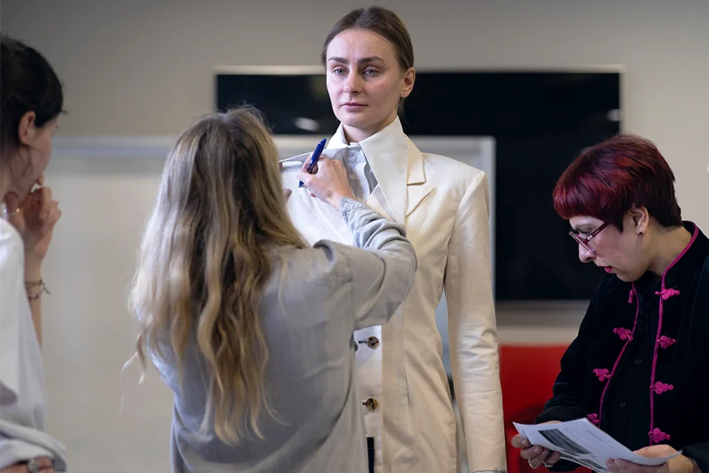 Studenti e docenti lavorano ai dettagli del capo sulla modella.