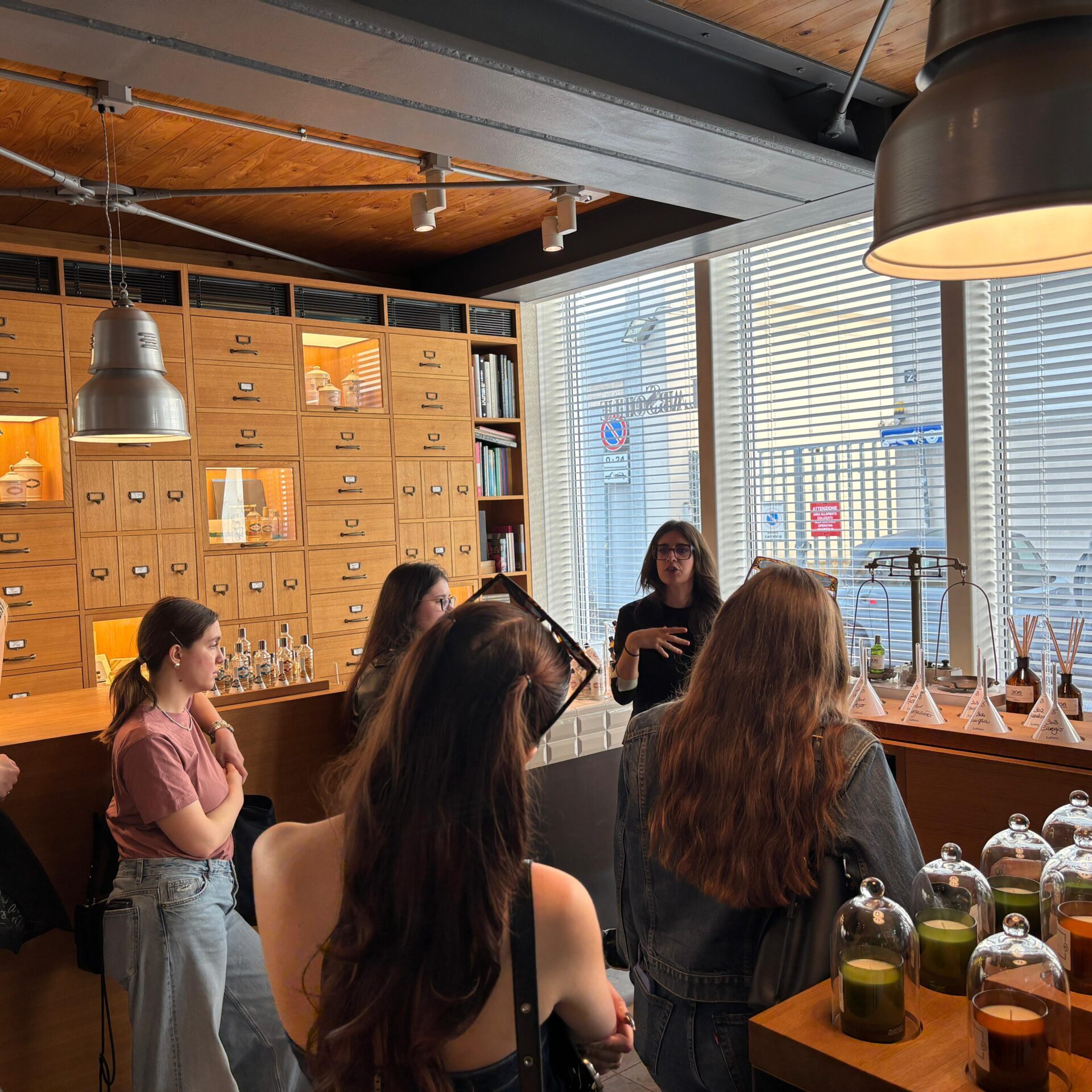 un gruppo di studentesse del Master all'interno di un locale con profumi che ascoltano una lezione