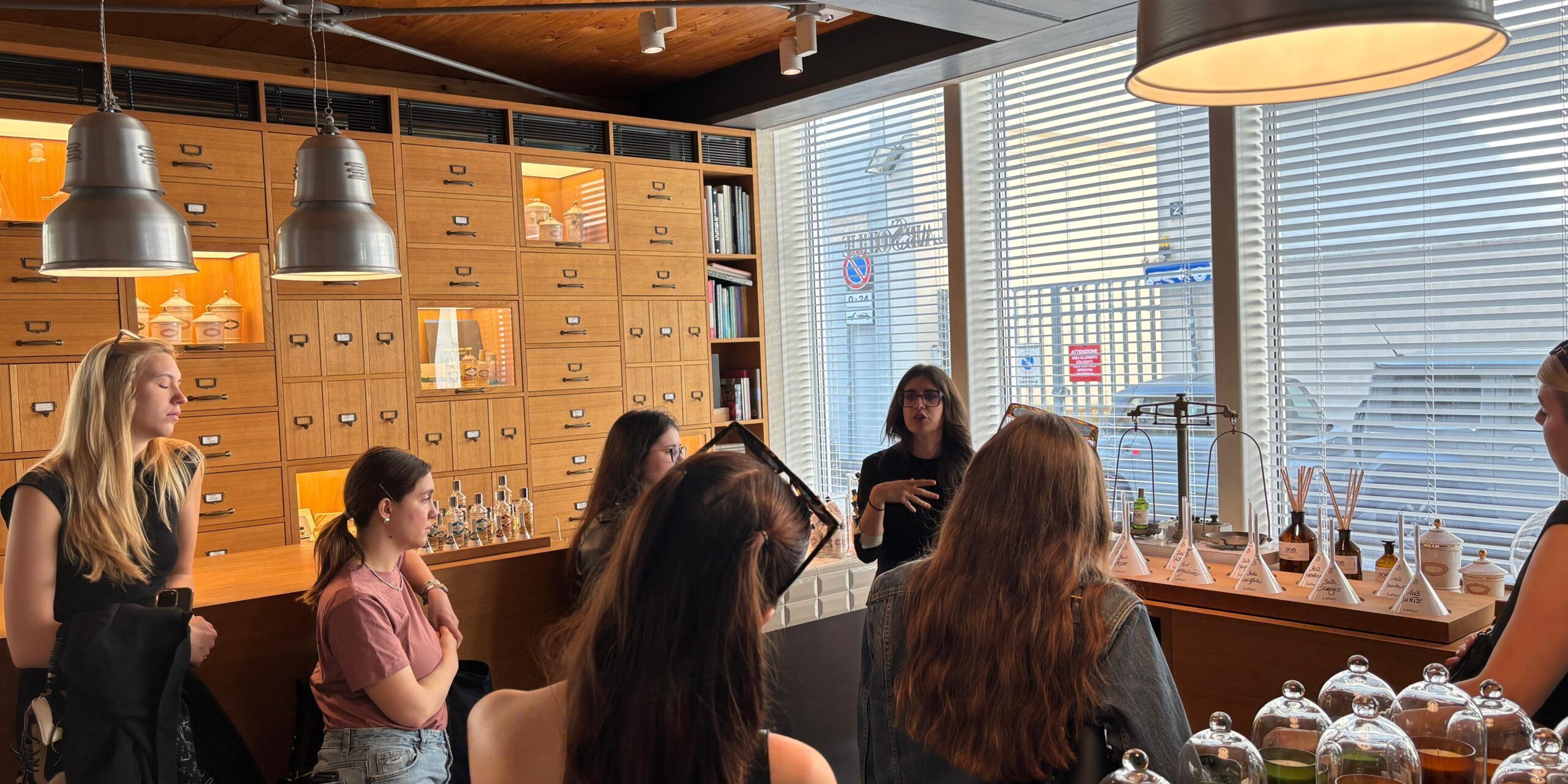 WhatsApp Image 2025-05-08 at 18.50.39 (2) un gruppo di studentesse del Master all'interno di un locale con profumi che ascoltano una lezione