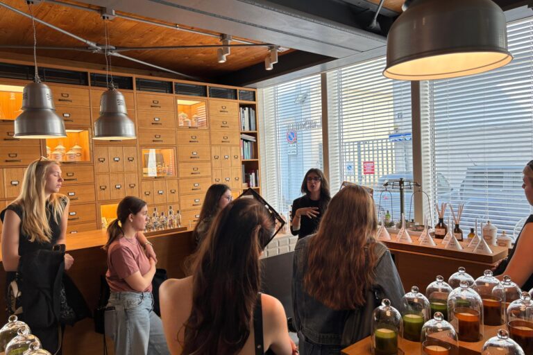 un gruppo di studentesse del Master all'interno di un locale con profumi che ascoltano una lezione