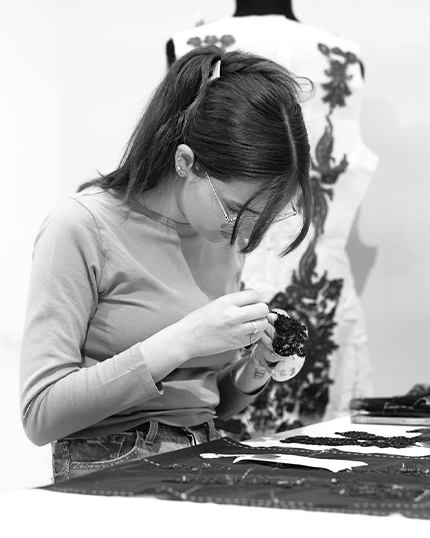 Studentessa ricama con fili e perline nere.