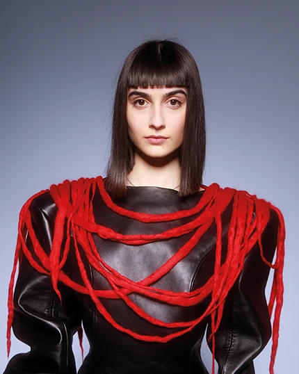 studentessa con indosso il proprio capo composto da una blusa nera con corde rosse in lana