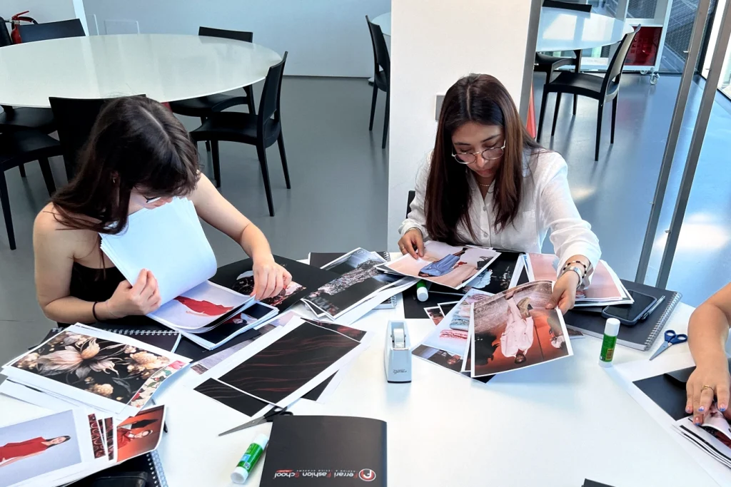 Studentesse sono sedute al tavolo e sfogliano le riviste per creare dei collage.