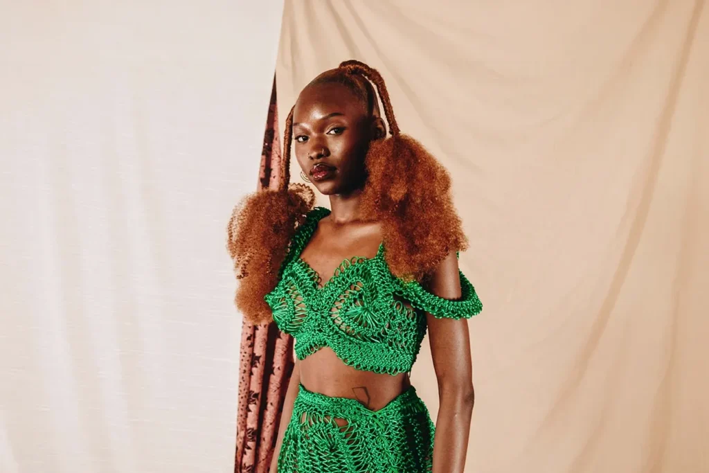 Una modella indossa un abito ricamato verde realizzato con materiali sostenibili.